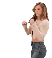 a woman in a crop top and jeans is standing with her hands in the air