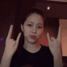 a woman in a black shirt is making a devil horns sign with her hands