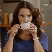 a woman drinking a cup of coffee with a max logo in the corner