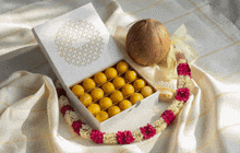 a white box filled with yellow balls sits on a table next to a coconut
