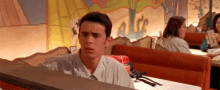 a man is sitting at a table in a diner looking at a menu .