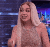 a woman with long blonde hair is wearing a very revealing top and making a funny face .