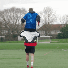 a man is carrying another man on his shoulders on a field