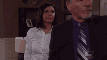 a man and a woman are standing next to each other in a living room .