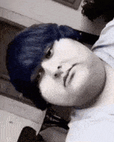a black and white photo of a person with blue hair looking at the camera