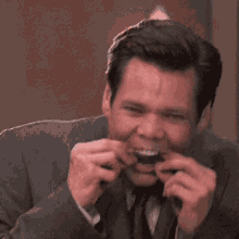 a man in a suit and tie is making a funny face with his hands