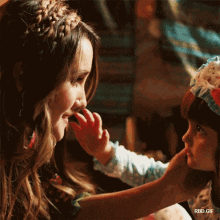 a little girl touching a woman 's face with her hand