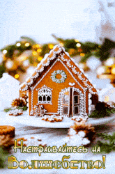 a gingerbread house sits on a white plate with a greeting in russian above it