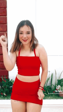 the girl is wearing a red crop top and a red skirt .