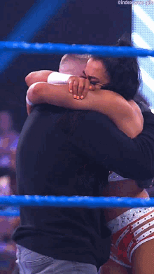 a woman in a wrestling ring holds a man 's neck in her hands