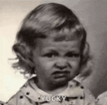 a black and white photo of a little girl with a very angry look on her face .