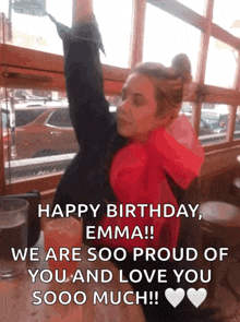a woman in a red jacket is sitting at a table with her arms in the air and a birthday message