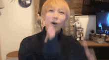 a man with blonde hair is making a funny face in front of a television