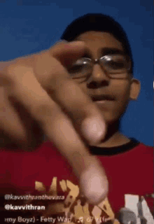 a young man wearing glasses and a red shirt is pointing
