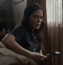 a woman is sitting on a couch holding a remote control .
