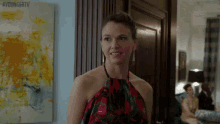 a woman in a halter top is standing in front of a painting that says youngertv