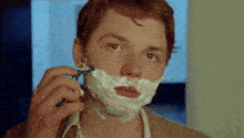 a man shaving his face with a razor and foam