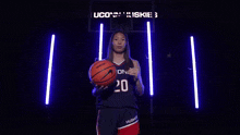 a female basketball player is holding a basketball in front of a scoreboard that says 23