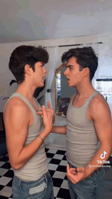 two men are looking at each other in a mirror .
