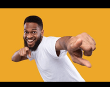 a man in a white shirt is pointing at the camera with his fingers .