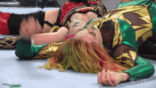 a woman in a green and gold outfit laying on the ground
