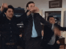 a group of men in suits are dancing in a living room .