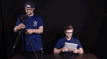 a man in a blue shirt with a star on it holds a camera