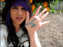 a woman with purple hair has a tattoo on her hand that says amberlynn dead