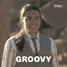 a man with long hair is smiling and the word groovy is on the screen