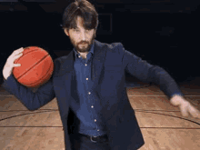 a man in a suit is holding a basketball on a court .
