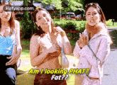 three women are standing next to each other in front of a car and one of them is asking another woman if she is looking fat .