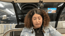 a woman in a denim jacket is sitting in a car