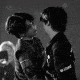 a black and white photo of two men looking at each other