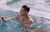 a shirtless man is taking a picture of himself in a pool .