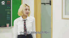 a girl in a white shirt and plaid tie stands in front of a blackboard with the letters twice on it