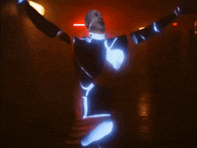 a man in a glow in the dark suit is dancing in a dark room