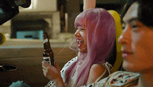 a woman with pink hair is holding a bottle of beer while sitting next to a man in a car .