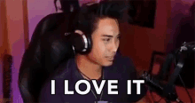 a man wearing headphones is sitting in a chair and says `` i love it '' .