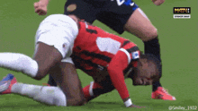 a soccer player is laying on the ground while another player kicks him