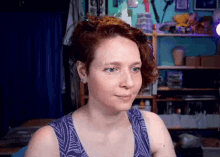 a woman with red hair and blue eyes is wearing a purple top