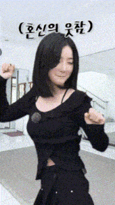 a woman in a black shirt is standing in a room with her eyes closed and her hands in the air .