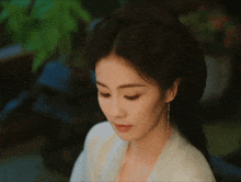 a woman with her eyes closed is wearing a white top