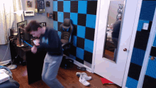 a man is playing a video game in a room with blue and black squares on the walls
