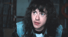 a young man with long hair is wearing a denim jacket with a patch on it that says fox