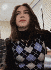 a woman wearing a plaid vest and black turtleneck
