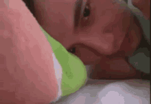 a close up of a person laying in bed with a pillow on their face .