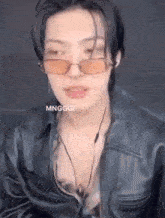 a young man wearing sunglasses and a leather jacket is talking .