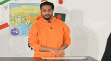 a man in an orange sweatshirt is standing in front of a map with the number 6 on it