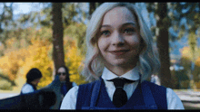 a girl with blonde hair wearing a blue vest and tie
