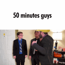 three men in suits and ties are standing in front of a door with the words 50 minutes guys written above them
